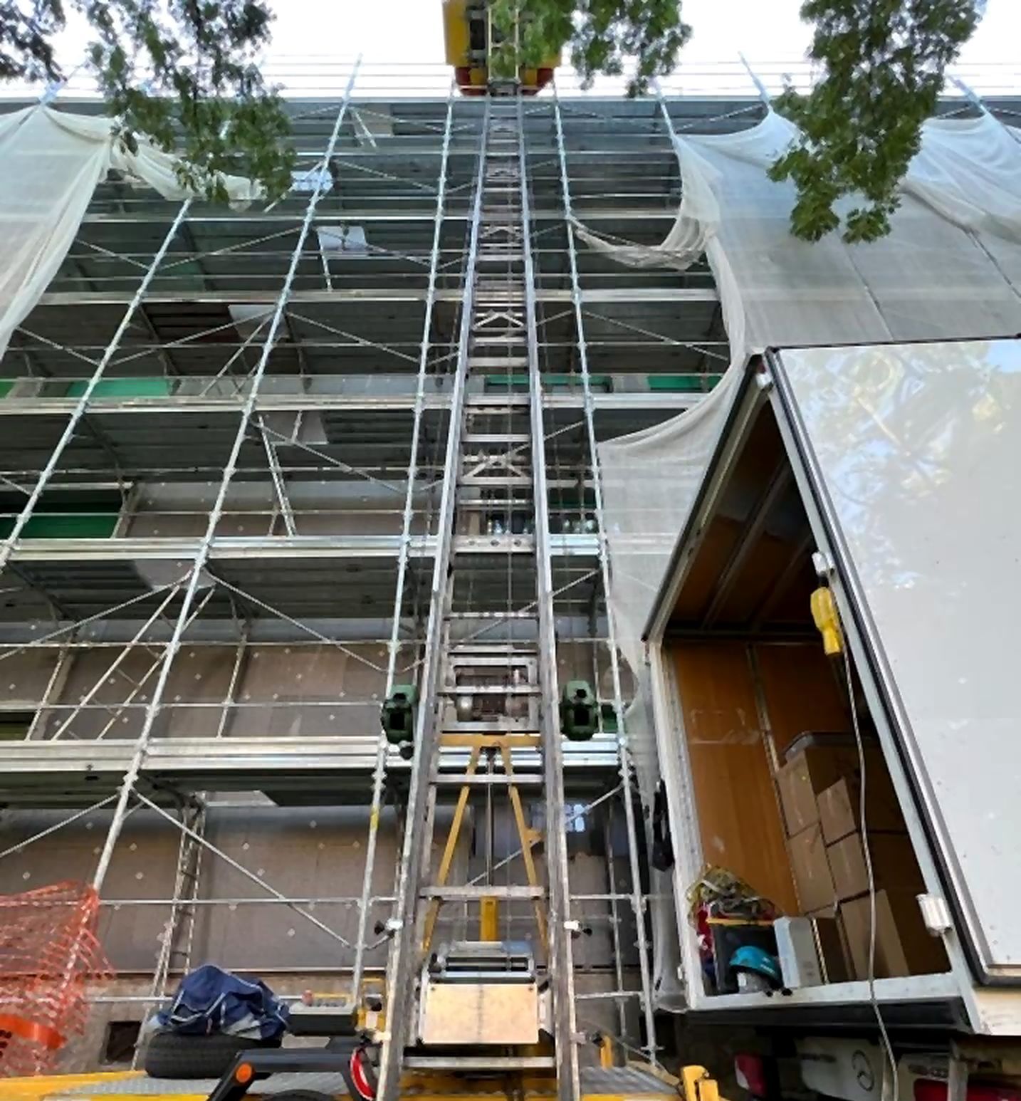 Trasloco con autoscala in un cantiere con ponteggi